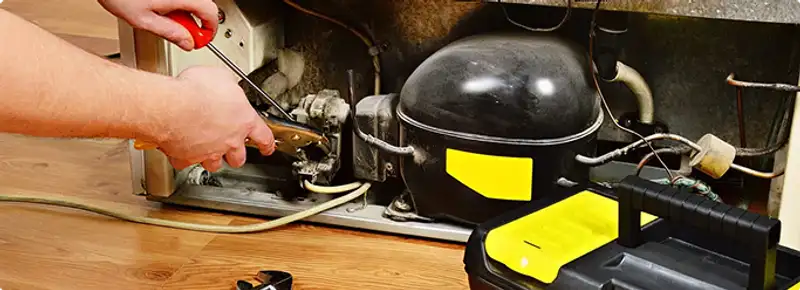 Refrigerator repair technician fixing the compressor and wiring in Rincon, GA