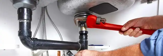 Garbage disposal repair technician tightening the sink drain and disposal connection in Savannah, GA