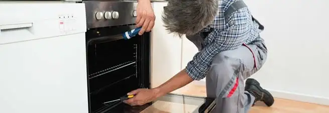 Oven repair technician inspecting and servicing an electric oven in Savannah, GA