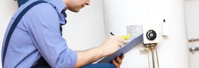Water heater repair technician inspecting the unit and recording service notes in Savannah, GA